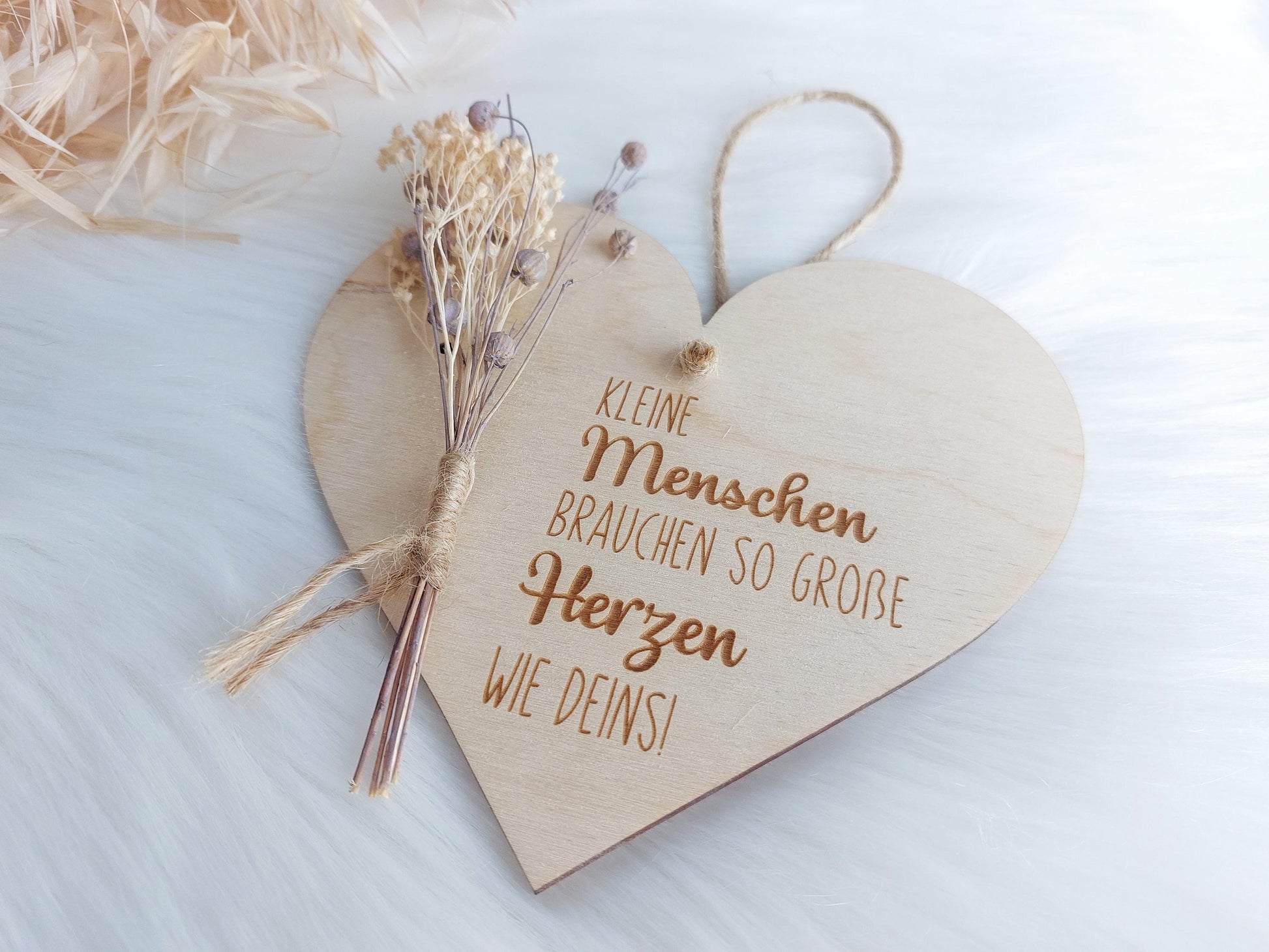 Einzelaufnahmen von graviertem Holzschild in Herzform.Beispieldeko: Trockenblumen. Spruch: Kleine Menschen brauchen so große Herzen wie deins!Besondere Geschenke für besondere Menschen. Ideal für Erzieherinnen und Erzieher oder Hebammen. Danke sagen