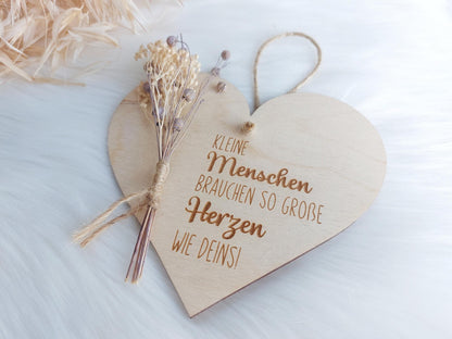 Einzelaufnahmen von graviertem Holzschild in Herzform.Beispieldeko: Trockenblumen. Spruch: Kleine Menschen brauchen so große Herzen wie deins!Besondere Geschenke für besondere Menschen. Ideal für Erzieherinnen und Erzieher oder Hebammen. Danke sagen